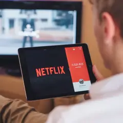 Chcesz wiedzieć, jak podłączyć tablet do telewizora przez HDMI? Na ekranie tabletu widać logo Netflix, a w tle telewizor.