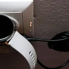 Biały smart bracelet podłączony do ładowarki w gniazdku. Dowiedz się, jak ładować swój smart bracelet.