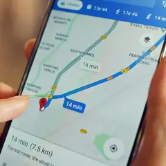 Palec dotyka ekranu smartfona z mapą, pokazując trasę i czas dojazdu. Dowiedz się, jak wysłać pinezkę, by udostępnić lokalizację.
