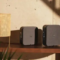 Dwa nowoczesne routery funbox 7 stoją obok siebie na drewnianej półce, obok plecionej lampy.