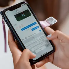 Dłonie trzymające smartfon, na ekranie czat Messenger. Zastanawiasz się, jak włączyć gry na Messengerze?