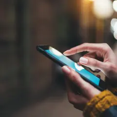 Dłoń dotyka ekranu smartfona, szukając informacji, jak wyczyścić schowek w telefonie.