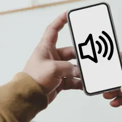 Dłoń trzyma smartfon z ikoną głośnika. Dowiedz się, jak wyłączyć dźwięk klawiszy Samsung, by pisać ciszej.