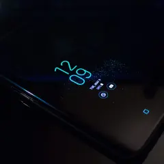 Czarny smartfon z włączonym ekranem, wyświetlającym godzinę 12:09 i datę. Dowiedz się, jak w prosty sposób pozbyć się nakładki ekranowej.