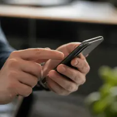 Dłonie trzymające smartfon, na ekranie którego widać komunikat o braku zasięgu Plus.