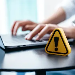 Ostrzeżenie na biurku obok laptopa. Zastanawiasz się, jak wylogować FB ze wszystkich urządzeń?
