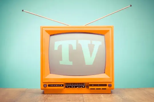 Pomarańczowy telewizor z wysuwanymi antenkami, na ekranie litery "TV".