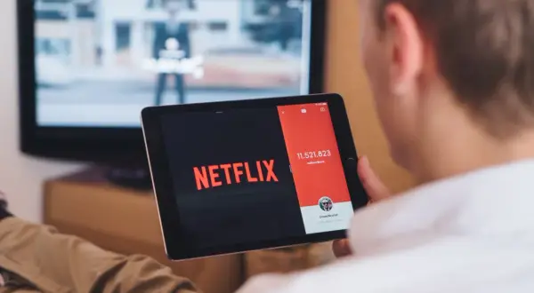Chcesz wiedzieć, jak podłączyć tablet do telewizora przez HDMI? Na ekranie tabletu widać logo Netflix, a w tle telewizor.
