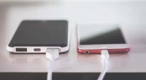 Dwa telefony podłączone do ładowania. Zastanawiasz się, dlaczego telefon wolno się ładuje? Może to wina kabla lub ładowarki.