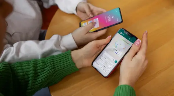 Dwie osoby korzystają z telefonów. Jedna z nich ma na ekranie mapę i klawiaturę, jak w systemie android 10.