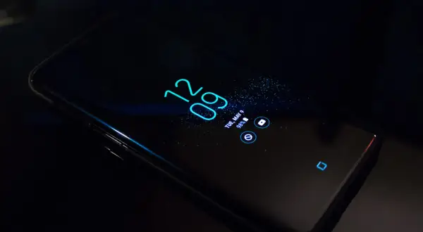 Czarny smartfon z włączonym ekranem, wyświetlającym godzinę 12:09 i datę. Dowiedz się, jak w prosty sposób pozbyć się nakładki ekranowej.