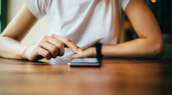 Dłoń dotyka ekranu telefonu, szukając instrukcji, jak zresetować telefon Redmi.