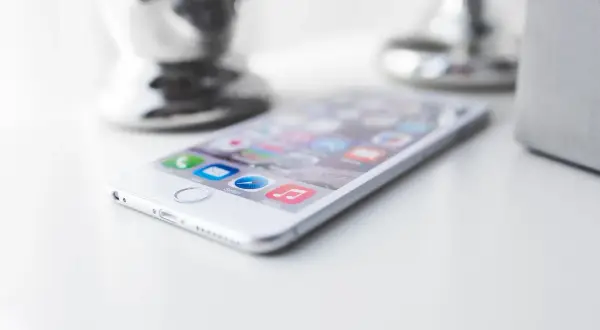 Biały iPhone z ikonami aplikacji na ekranie. Dowiedz się, jak wyczyścić telefon ze śmieci, by działał szybciej.