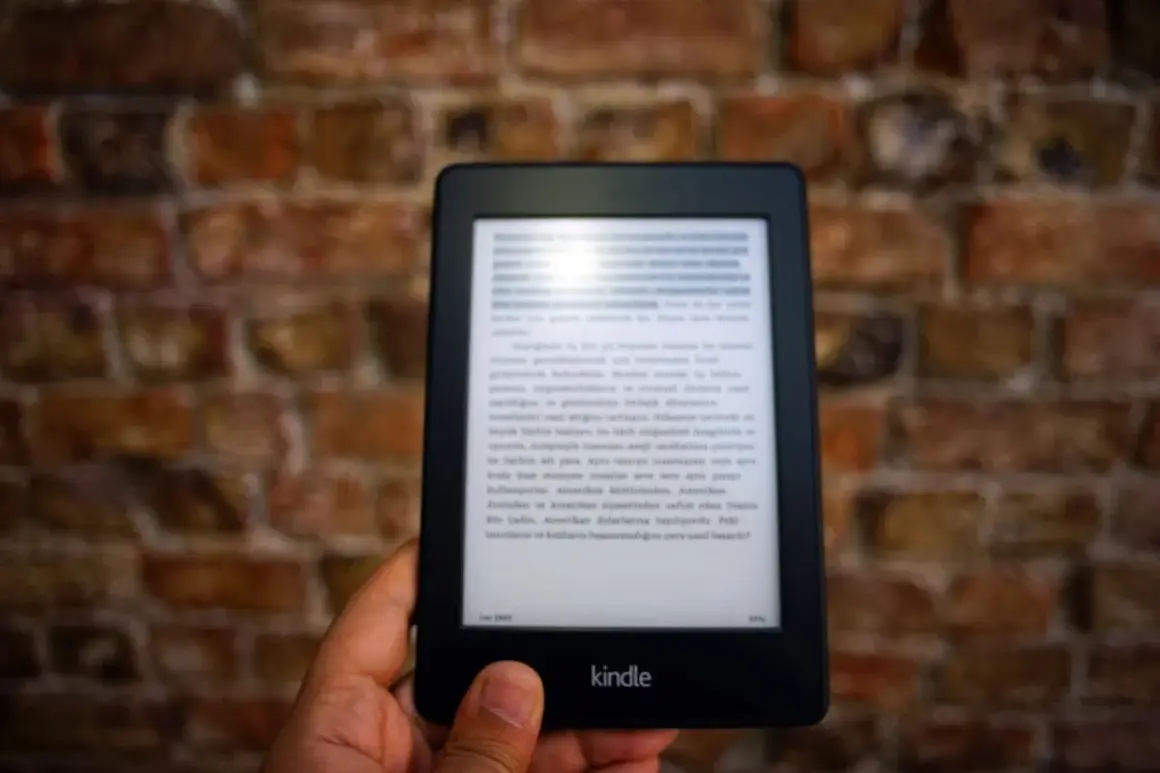 Dłoń trzyma czytnik Kindle z tekstem. Komputer nie widzi Kindla, mimo że jest podłączony.