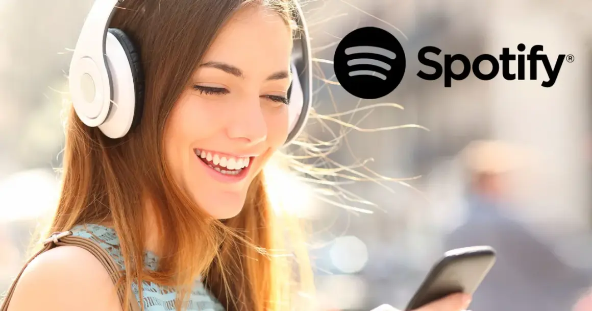 Uśmiechnięta dziewczyna w słuchawkach słucha muzyki na Spotify. Dowiedz się, jak zmienić nazwę użytkownika na Spotify.