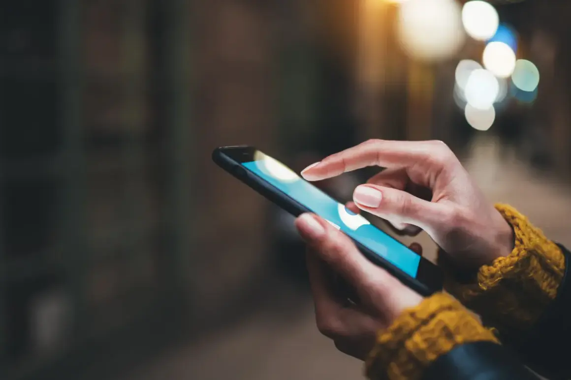 Dłoń dotyka ekranu smartfona, szukając informacji, jak wyczyścić schowek w telefonie.
