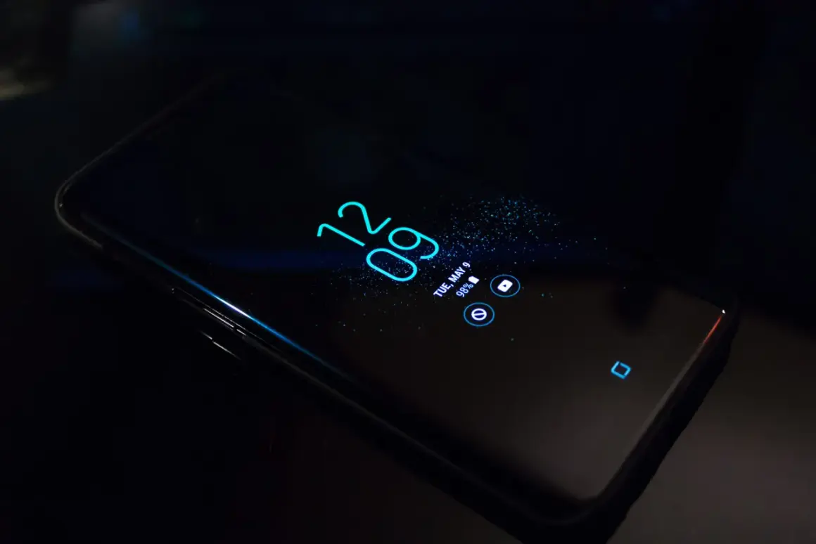 Czarny smartfon z włączonym ekranem, wyświetlającym godzinę 12:09 i datę. Dowiedz się, jak w prosty sposób pozbyć się nakładki ekranowej.