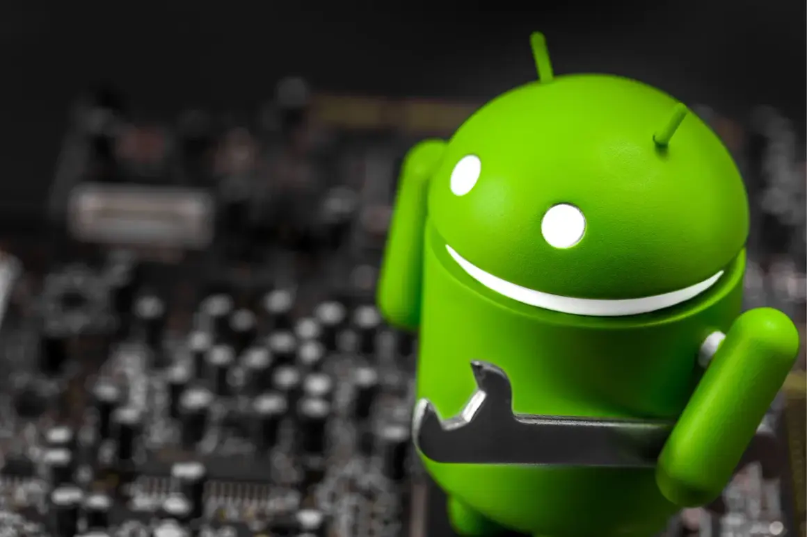 Zielony robot Android z kluczem, jakby wykryto nakładkę ekranową. W tle widać rozmazaną płytę główną.