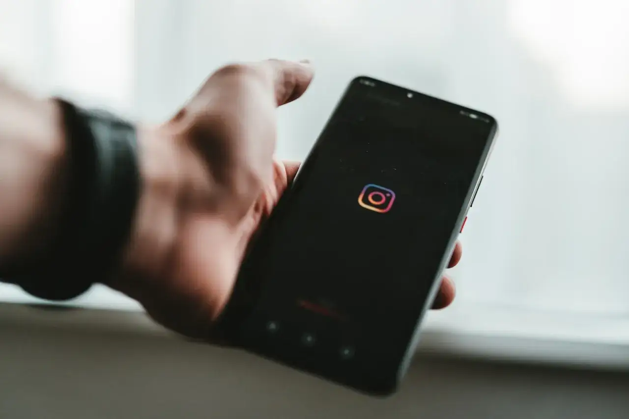 Dłoń trzyma smartfon z logo Instagrama. Dowiedz się, jak przywrócić zarchiwizowane zdjęcia na Instagramie.
