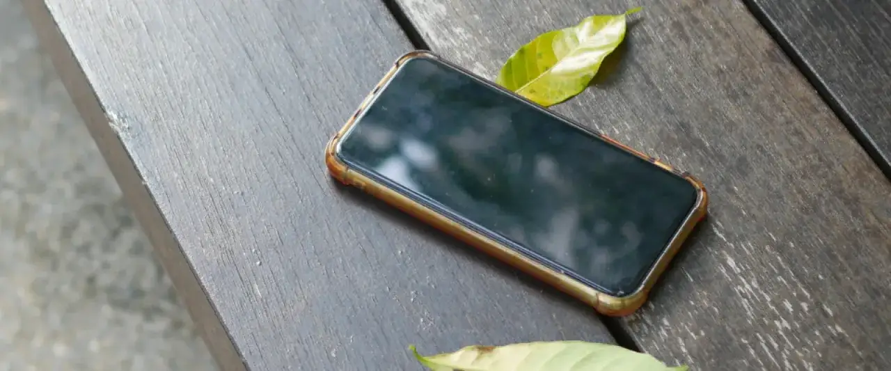 Smartfon leży na drewnianym blacie. Jak namierzyć wyłączony telefon? Może pomoże lokalizacja ostatniego połączenia lub sygnał GPS.
