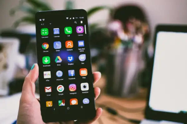 Dłoń trzyma smartfon z ikonami aplikacji. Jeśli masz problem, jak zresetować zablokowany telefon, ten ekran może pomóc.
