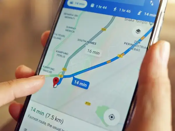 Palec dotyka ekranu smartfona z mapą, pokazując trasę i czas dojazdu. Dowiedz się, jak wysłać pinezkę, by udostępnić lokalizację.