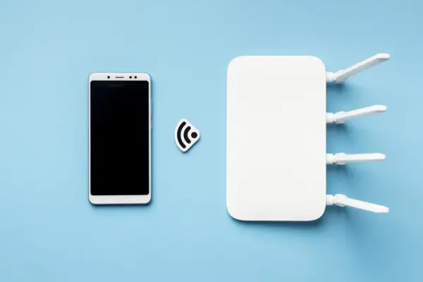 Smartfon i router Wi-Fi symbolizują, jak udostępnić internet z telefonu na laptopa.