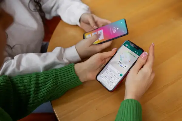 Dwie osoby korzystają z telefonów. Jedna z nich ma na ekranie mapę i klawiaturę, jak w systemie android 10.