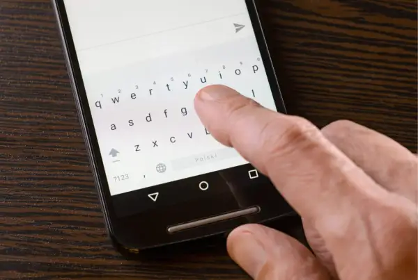 Palec naciska klawisz "u" na klawiaturze telefonu, szukając sposobu, jak wyłączyć autokorektę.