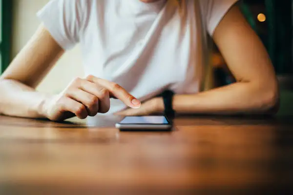 Dłoń dotyka ekranu telefonu, szukając instrukcji, jak zresetować telefon Redmi.