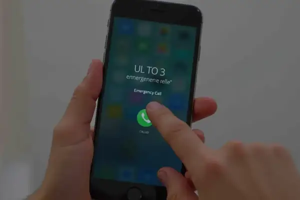 Dłoń naciska przycisk "Emergency Call" na ekranie telefonu, pokazując, jak odblokować telefon przez połączenie alarmowe.