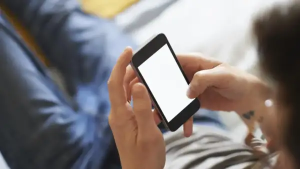 Dłonie trzymają smartfon, ekran świeci pustym blaskiem. Zastanawiasz się, jak schłodzić telefon? Oto kilka wskazówek.