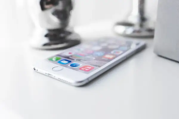 Biały iPhone z ikonami aplikacji na ekranie. Dowiedz się, jak wyczyścić telefon ze śmieci, by działał szybciej.